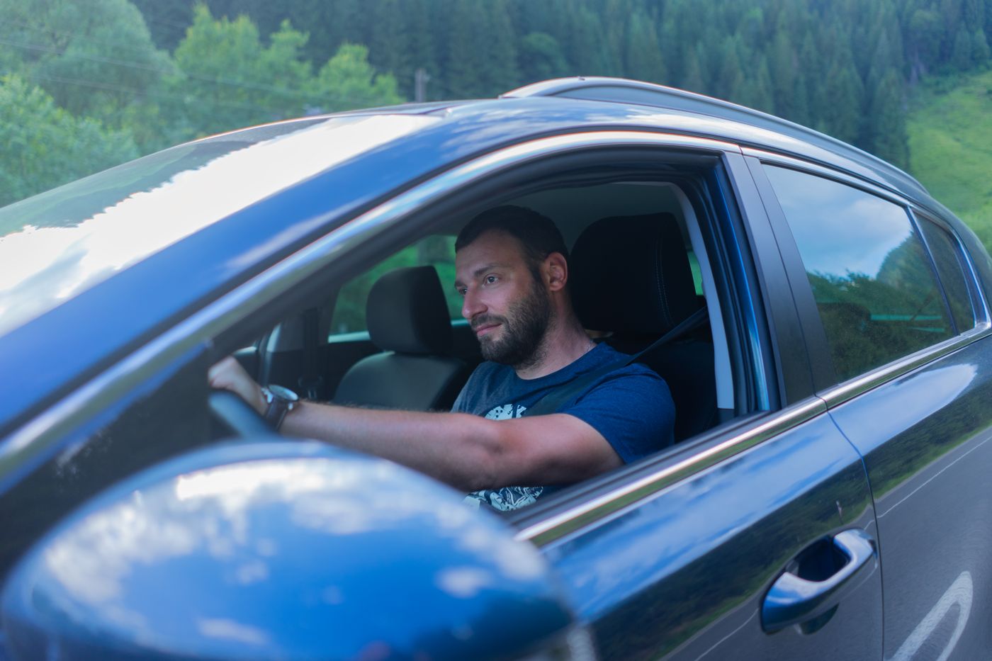 Homme conduisant une voiture dans un environnement verdoyant